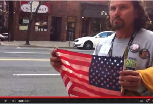 A photo op dreamed up by a PR firm: Carlos displays his blood soaked American flag.